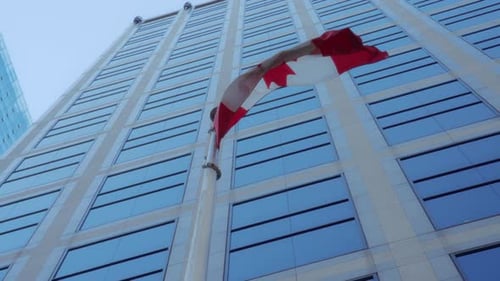 Canadian Flag Waves Beside Tall City Building