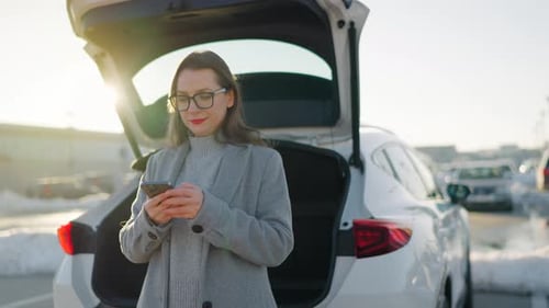 Woman Uses Phone near Car on Bright Day