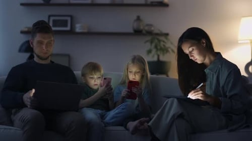 Family Using Technology Together on Sofa at Night