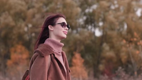 Young Woman Wearing Sunglasses in Autumnal Nature Scene