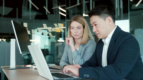 Two Professionals Collaborating on a Laptop in Office