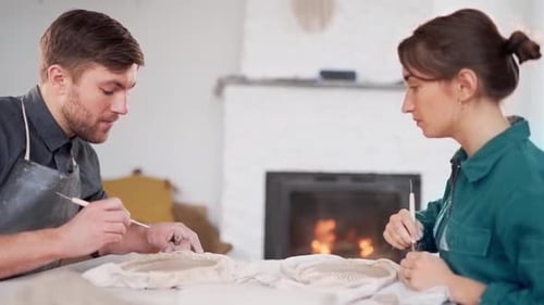 pottery school, man and woman cut a pattern on clay