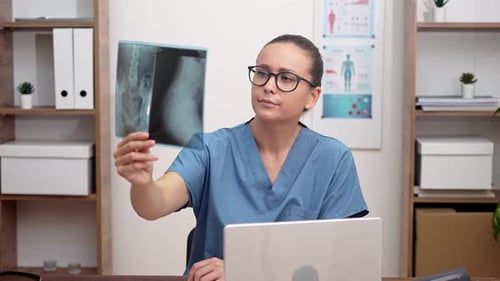 Doctor in Blue Scrubs Looking at Radiology Xray Film Diagnose Patient in the Hospital