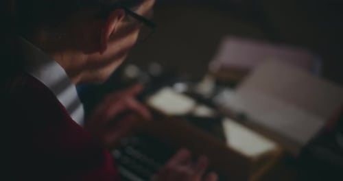 Man Typing on Keyboard in Dimly Lit Room