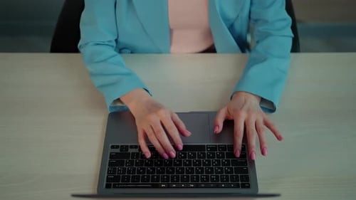 Woman Typing on Laptop at Desk in Workplace