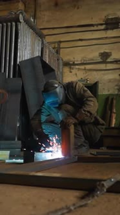 Torch Worker with Mask Connects Details of Beam Carcass