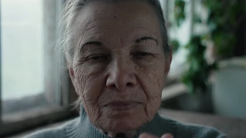 Senior Woman Covers Face with Hands Indoors