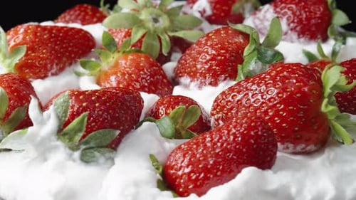 A large plate with whipped cream and strawberries, slowly rotating in close-up.