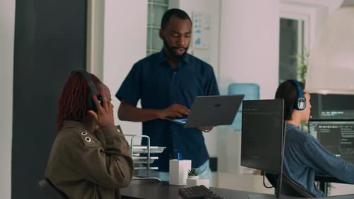 Equipo de desarrolladores de software habla sobre la ejecución del código fuente en una computadora portátil