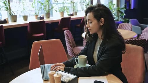 Caucasian Woman Sitting on a Round Table Inside of Cafe