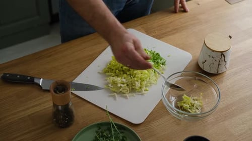 Handsome Bearded Man is Preparing Green Fresh Vegan Salad in the Kitchen at Home Male Cutting