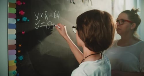 Primary School Student Solving Mathematical Equation Writing on the Board with Chalk