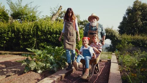 Family Strolling Through Garden With Children in Wheelbarrow