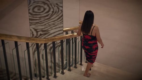 Nighttime Scene of Asian Woman Descending Marble Staircase with Poised Elegance in Hotel Foyer