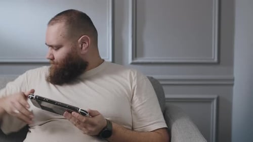 Bearded Man Playing Handheld Video Game