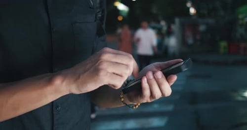 Adult Using Mobile Phone on City Street at Night