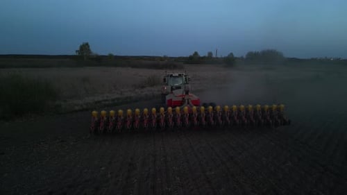 Green tractor works on the field sowing sunflower. Tractor planting corn in Ukraine
