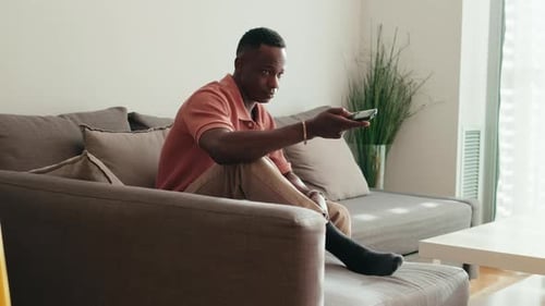 Side view of Young Man Watching TV on Sofa at Home