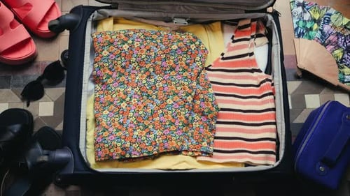 A Person Packing a Suitcase or Luggage for Travel Top View of a Female Traveler Packing Clothes Into