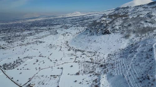 Aerial View of Winding Highway Through Snow-Covered Mountains