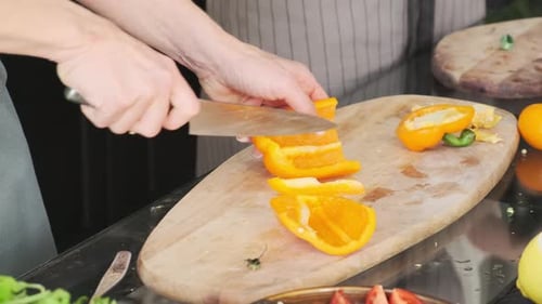 Hands Slicing Yellow Pepper on Cutting Board