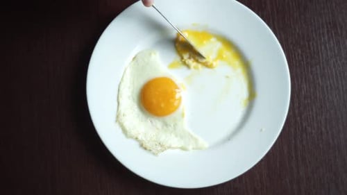 Eating Fried Eggs. Morning Breakfast on White Plate. Top View of Hand