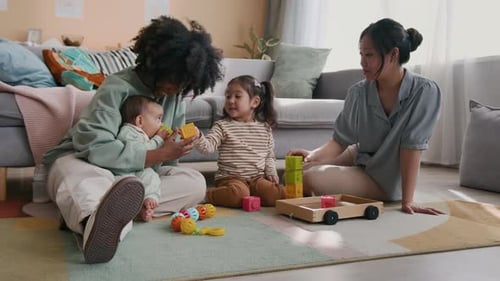 Two Adults Play with Children on Rug