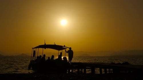 Silhouette of People Boarding Boat at Sunset