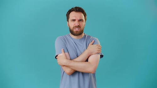 Man Shivering and Rubbing Arms in Cold
