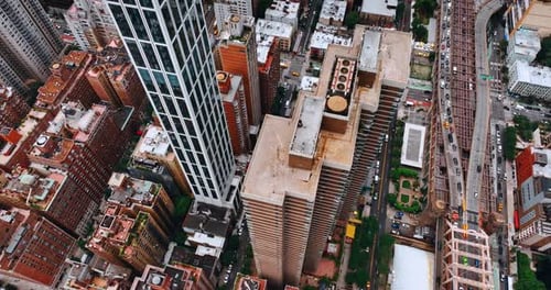 Lowering above the tops of high buildings at downtown. Numerous cars move by New York roads.
