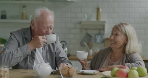 Elderly Couple Conversing Over Tea at Kitchen Table