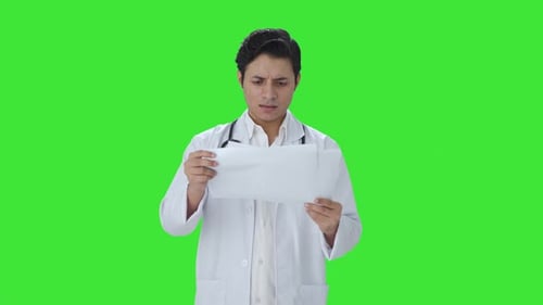 Confused Indian doctor checking medical reports Green screen