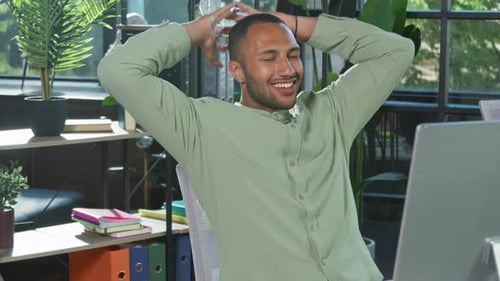 Satisfied Young Man Relaxing at Office Desk