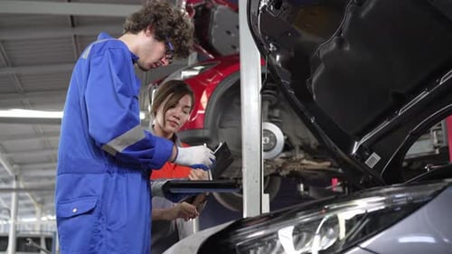 Mechanic checking and repairing with sales agent employee at auto repair shop. After service car mai