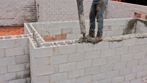 Construction Worker Laying Concrete Blocks at Building Site During Daylight Hours in Residential