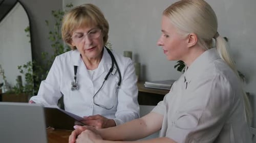 Two Happy Women a Doctor and a Patient in a Medical Office Discuss Treatment