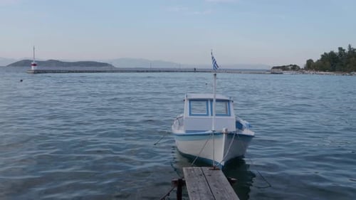 A small boat in the Aegean sea water and a small dock in the port of Limerias in Thasos, Greece.