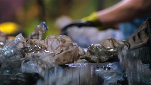 Plastic garbage on a conveyor belt at waste recycling factory. Workers on the background