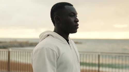 Young man walking by the sea on the promenade