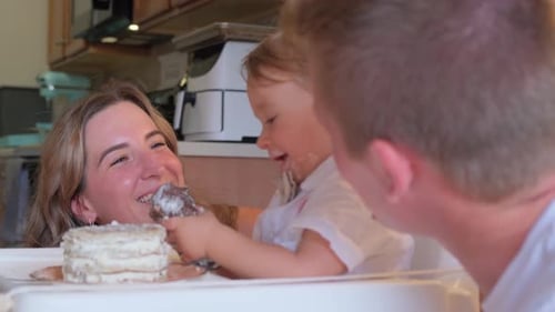 Toddler Eating Birthday Cake with Parents at Home