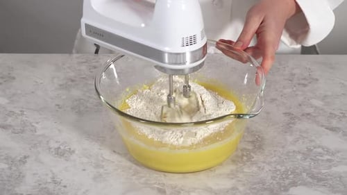 Time Lapse Close Up View Mixing Ingredients in a Glass Mixing Bowl to Bake Funfettti Bundt Cake
