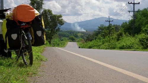 Backpacker bicycle parked on the shoulder of a rural road in Southeast Asia. Stopping on the trip