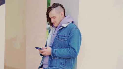 Man Leans on Wall Using Smartphone