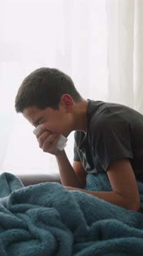 Teenage Boy Suffering from Cold Blowing Nose