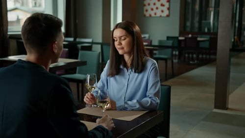 A date in a hotel restaurant a man and a woman drink white wine in glasses the face of smiling girl