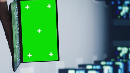 Person Holds Laptop with Green Screen in Office