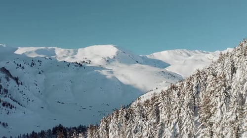 Aerial view of snow mountain range landscape under a blue sky.