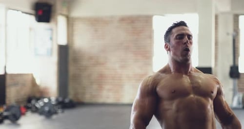 Muscular Man Lifts Weights in Gym