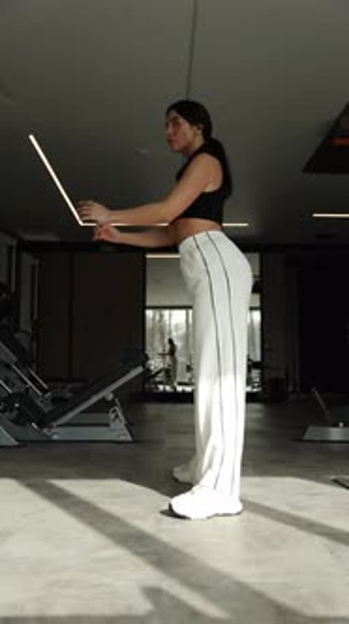 Confident Woman Showcasing Strength Training with Advanced Gym Equipment in Luxury Fitness Center