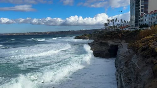 King tide at La Jolla Cove skyline view over waves crashing on clliffs birds flying by..